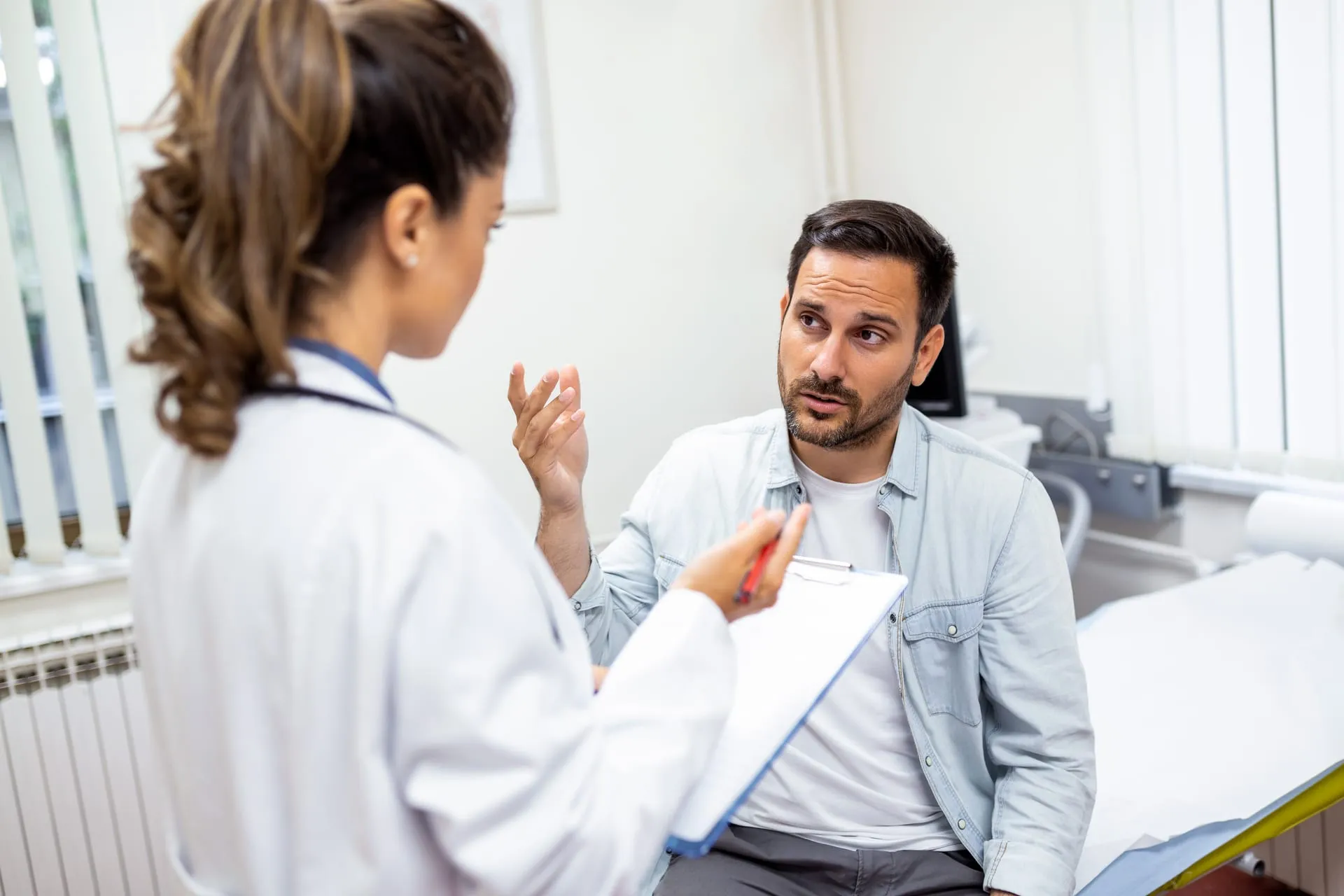 Ärztin spricht mit einem Patienten im Behandlungszimmer