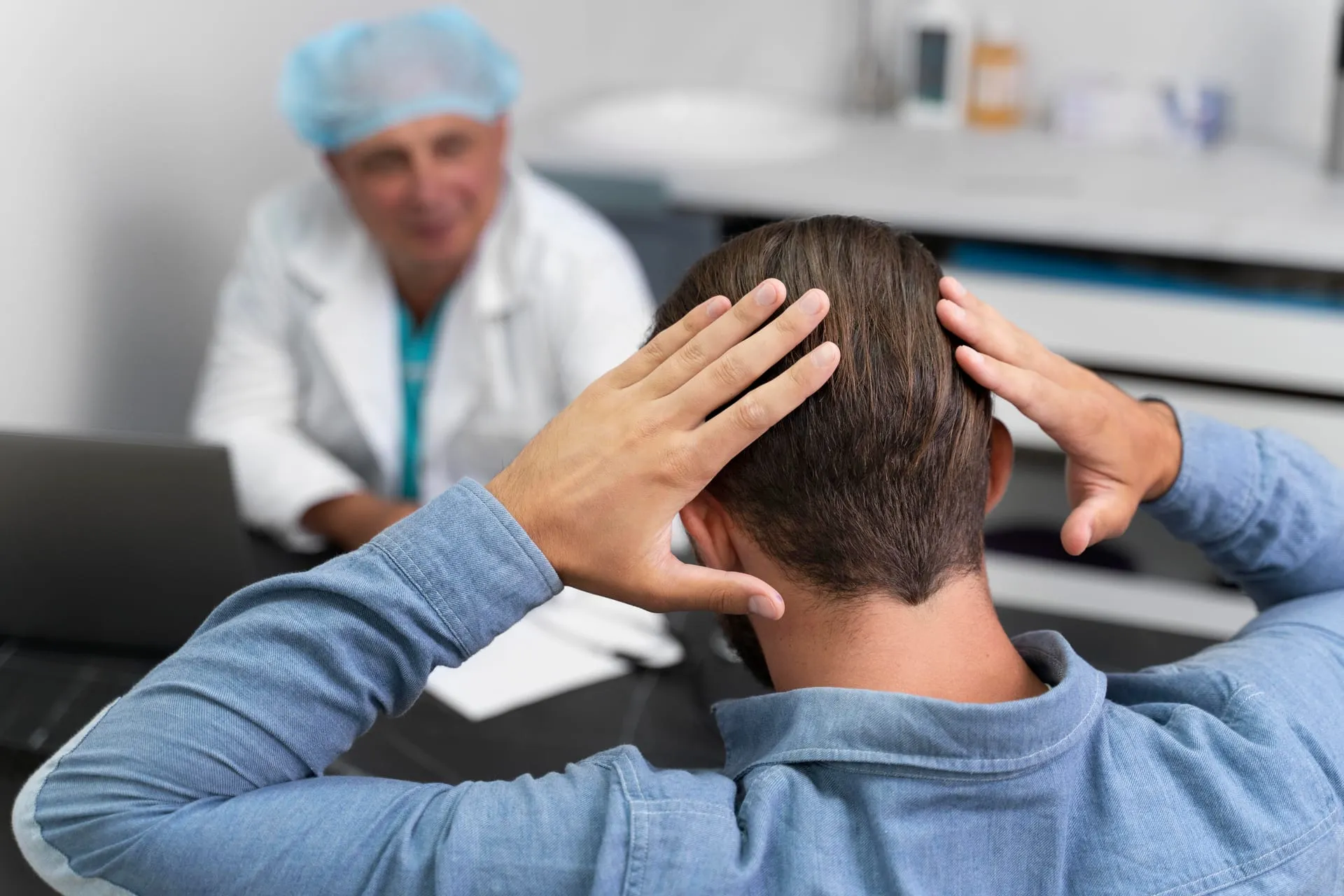 Man touching the back of his head with a doctor in the background