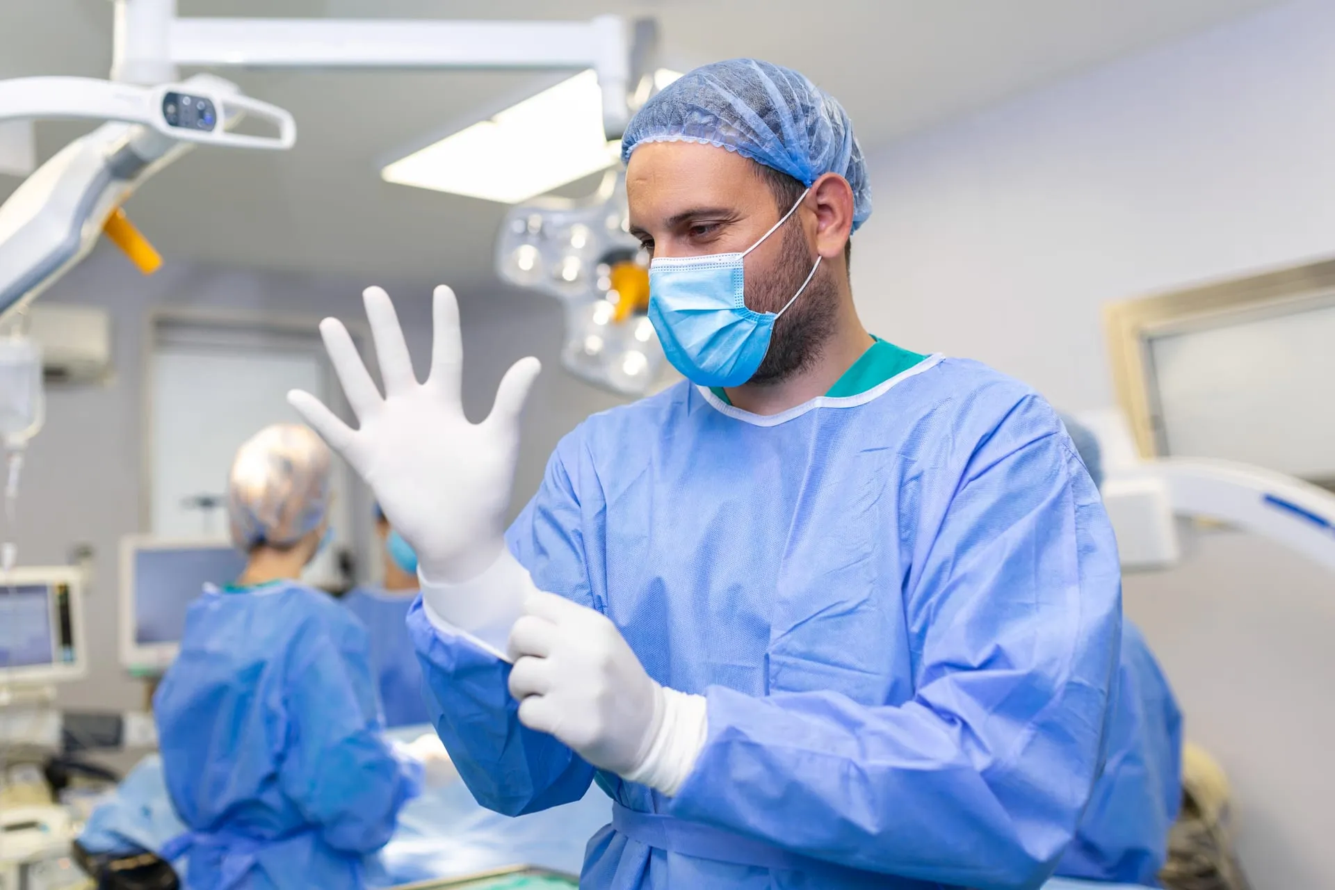 Chirurg zieht im Operationssaal sterile Handschuhe an