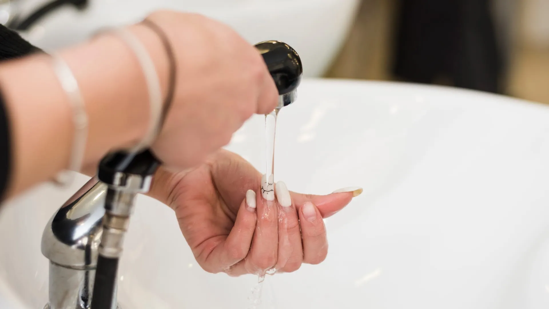 Hand prüft die Wassertemperatur unter der Brause